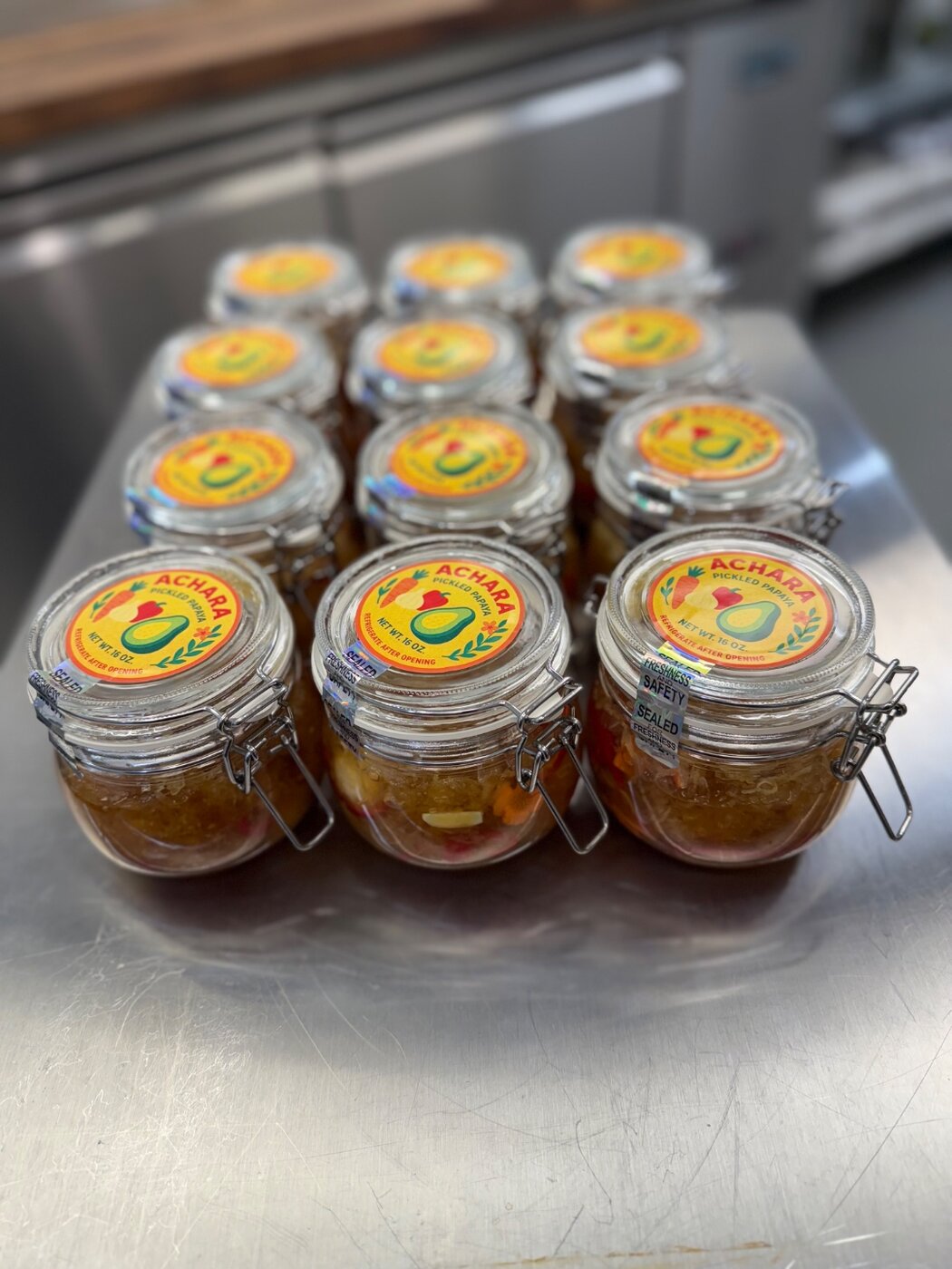 Twelve jars of atchara arranged on a metal tray