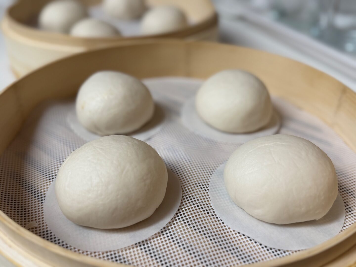 Freshly steamed bao in a bamboo basket