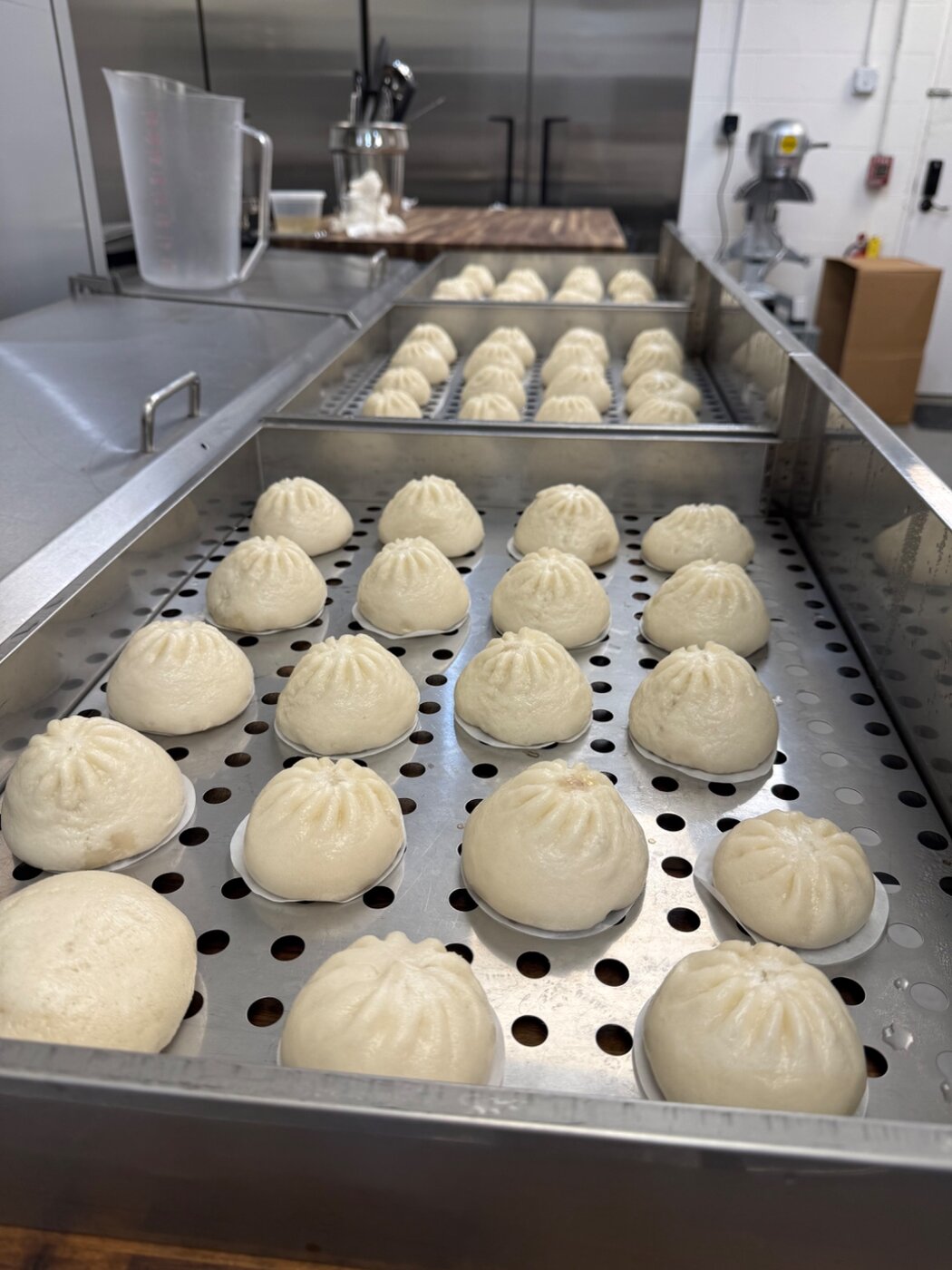 Close-up of hand-pleated bao in a steamer tray