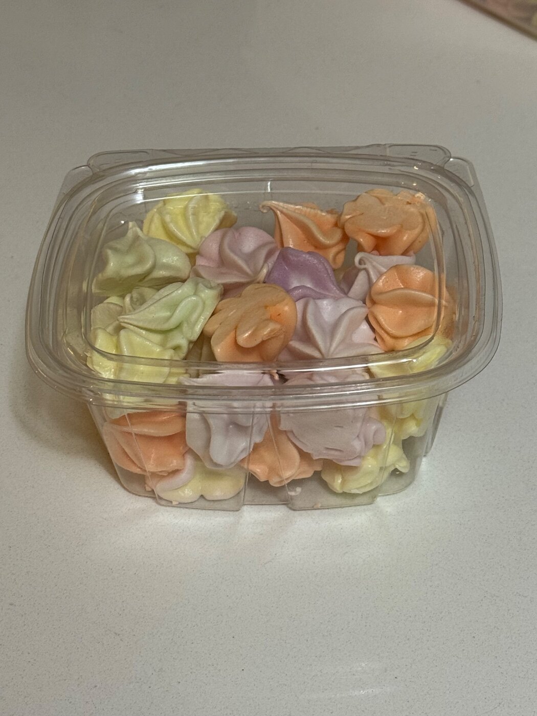 Assorted pastel meringue cookies in a container