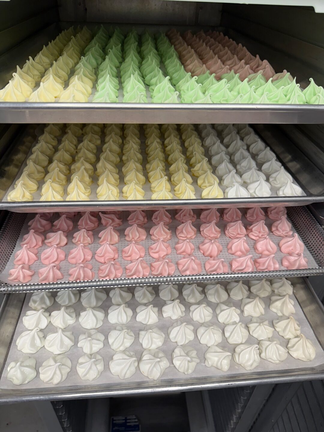 Trays of pastel meringue cookies in rainbow colors